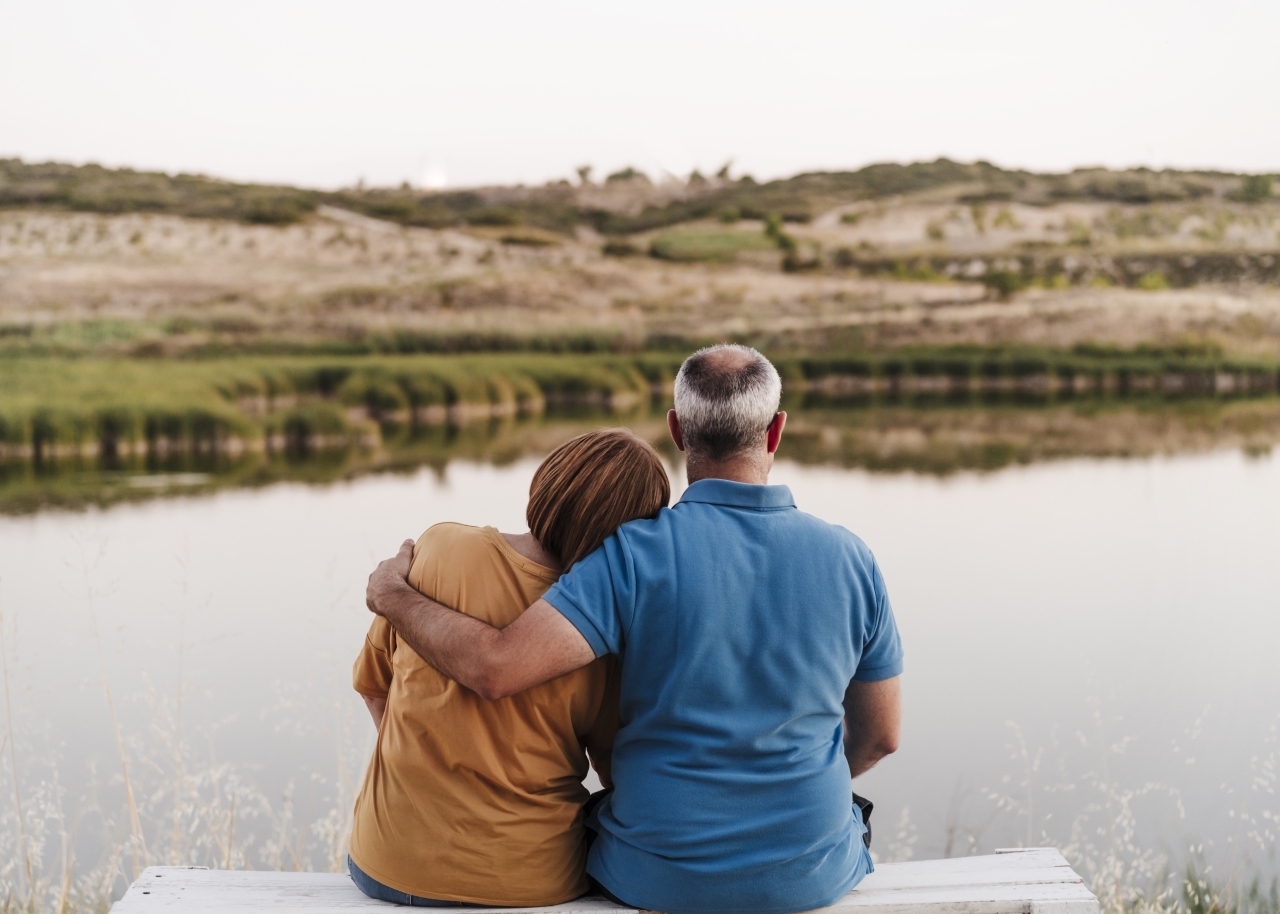 resting with head on son's shoulder while sitting on bench near lake